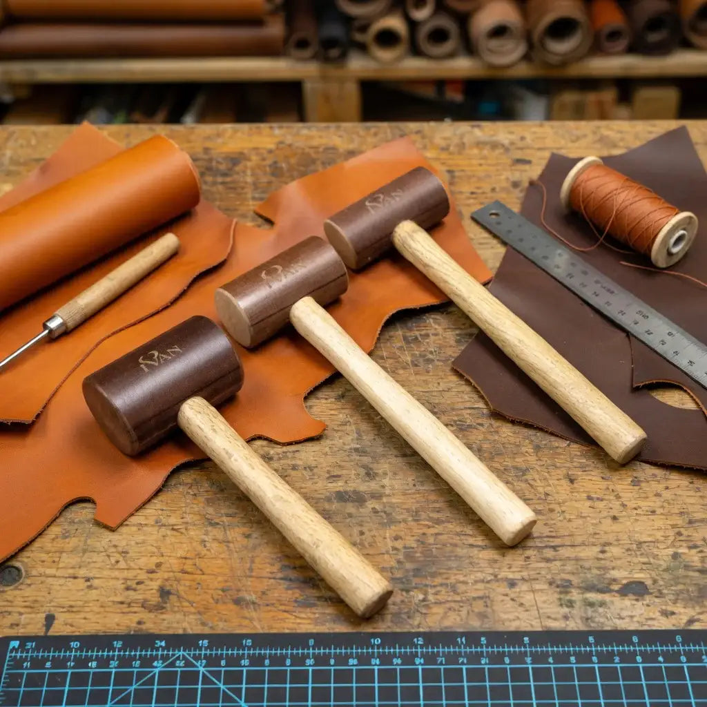 Lederwerkzeug Set mit Holzhammer, Lineal, Garn und Leder auf Werkbank, Lederhandwerk