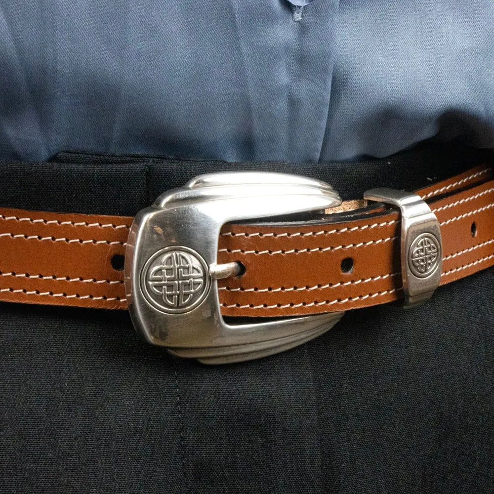 Brauner Ledergürtel mit auffälliger silberner Schnalle und Ziernähten an schwarzer Hose