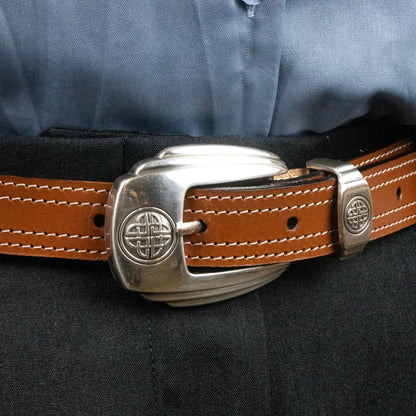 Brauner Ledergürtel mit auffälliger silberner Schnalle und Ziernähten an schwarzer Hose