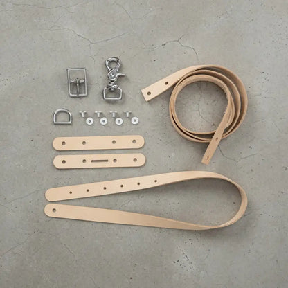 DIY Set: naturfarbene Lederstreifen, Metallteile und Werkzeuge für Lederhandwerk auf Beton