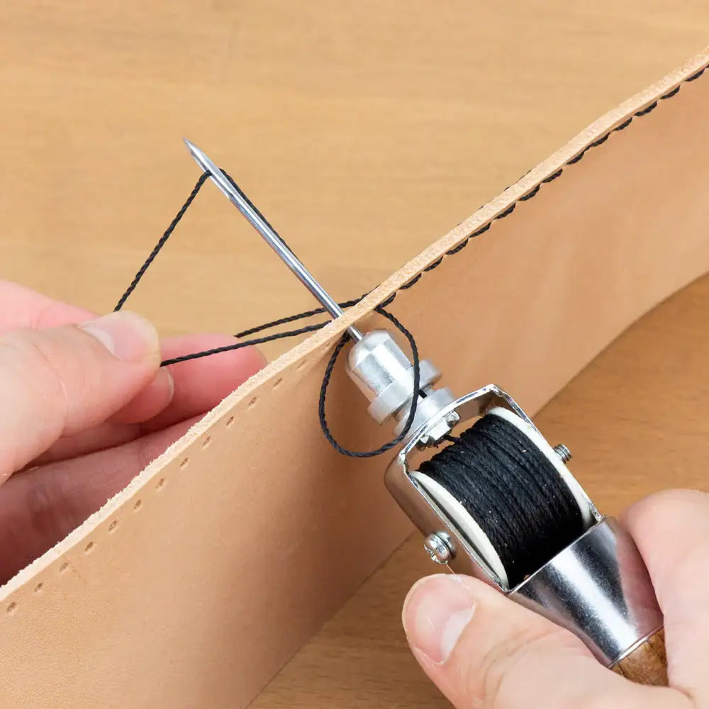 Lederhandwerk: Hand näht Leder mit Schwarzer Faden und Ahle auf Holzuntergrund