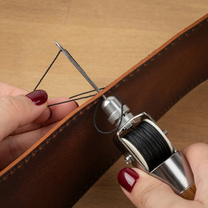 Hand näht braunes Echtleder mit Nähahle und schwarzem Faden, Lederhandwerk Detail