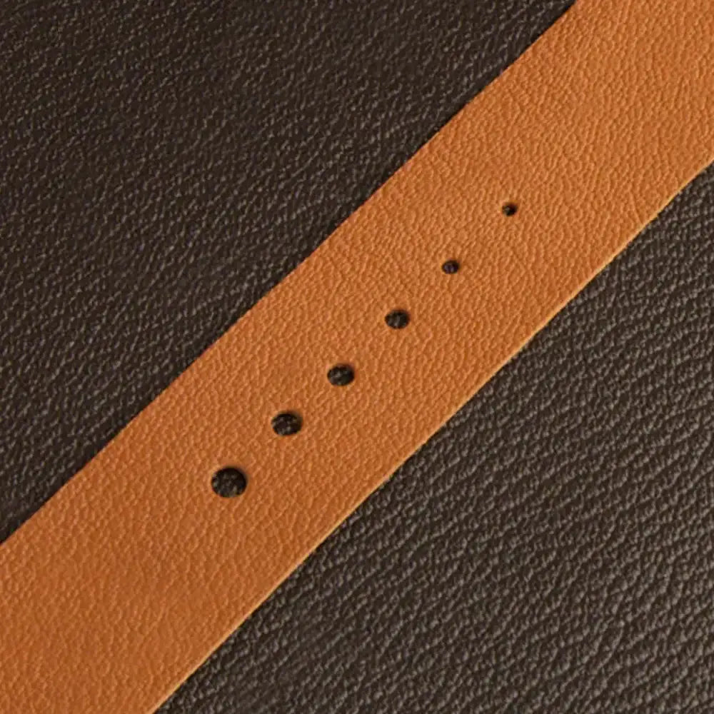 Nahaufnahme eines gelochten Lederriemens auf dunkelbraunem Leder für Lederhandwerk