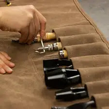 Lederwerkzeug Set in brauner Rolltasche, Hand greift nach Werkzeug, geeignet für Handwerker