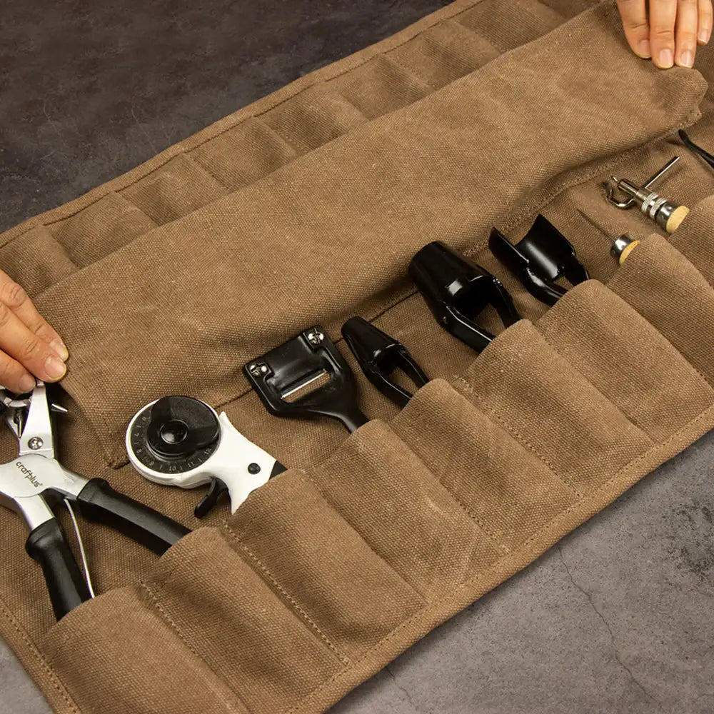 Lederwerkzeug-Set in brauner Canvas-Rolle auf dunkler Arbeitsfläche, ideal für Handwerker