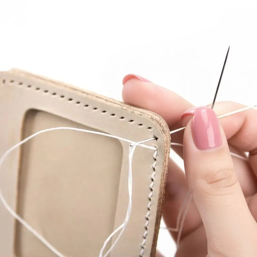 Hand näht helles Leder mit Nadel und weißem Faden, Nahaufnahme Handarbeit