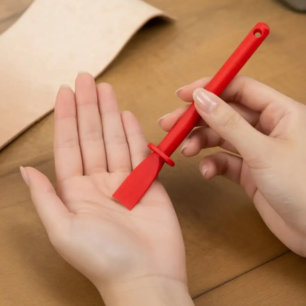 Rotes Lederwerkzeug aus Kunststoff für Bastler, Nahaufnahme auf Holz mit Lederstück