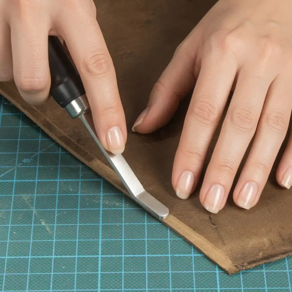 Hand schneidet Leder mit Werkzeug auf Schneidematte, Lederwerkzeug, Handwerksarbeit