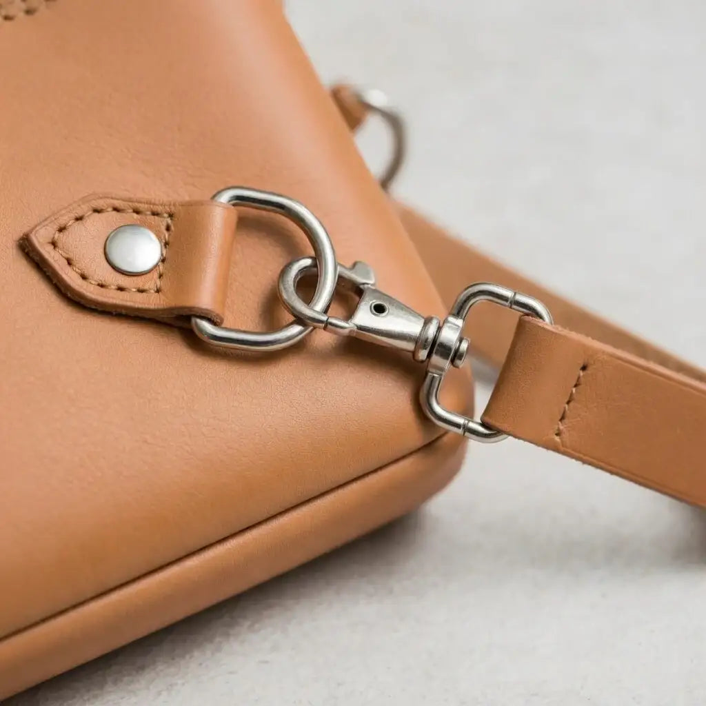 Detailaufnahme einer hellbraunen Ledertasche mit Metallverschluss und sauberer Naht