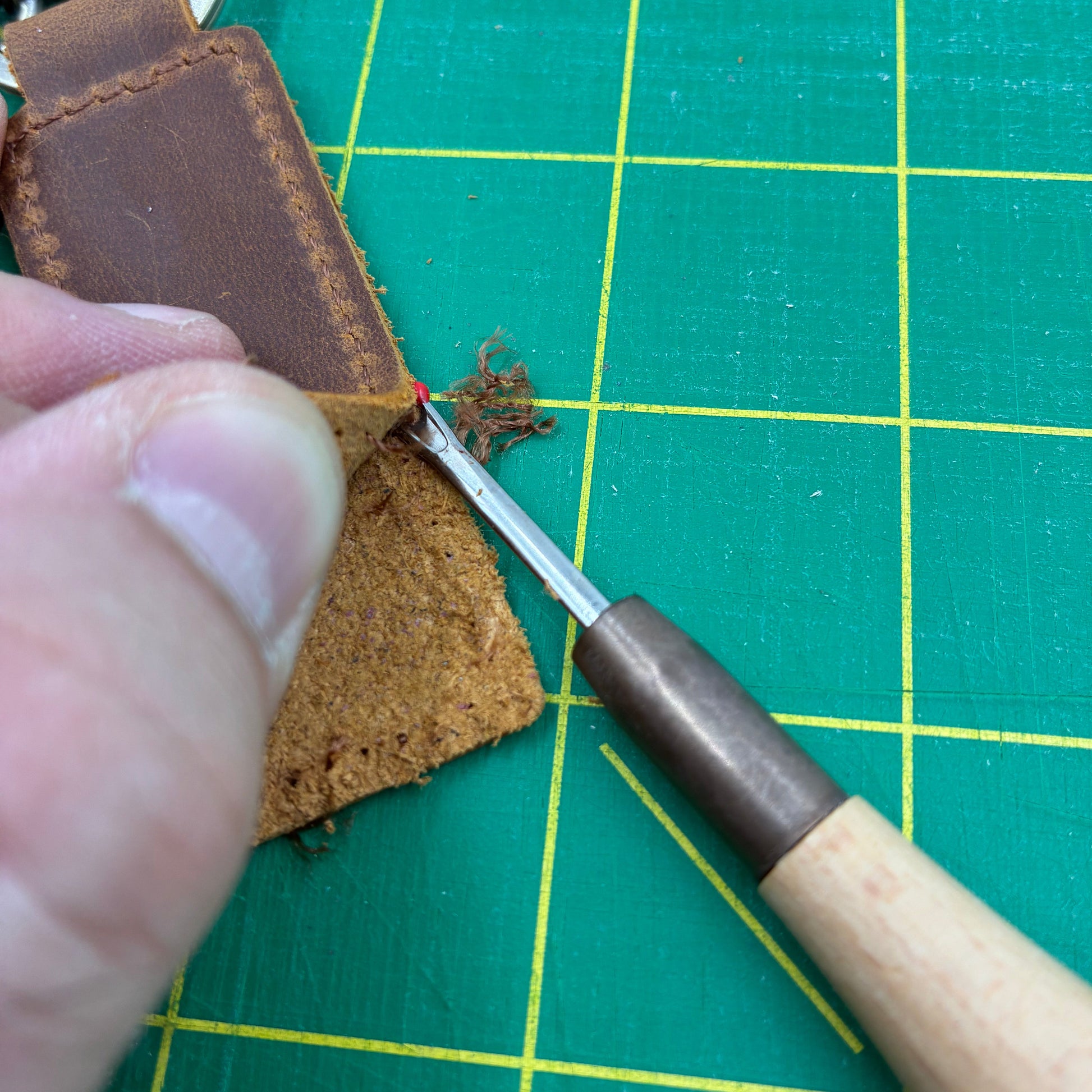 Lederbearbeitung mit Werkzeug auf grüner Schneidematte – perfekt für Lederprojekte und Handwerk