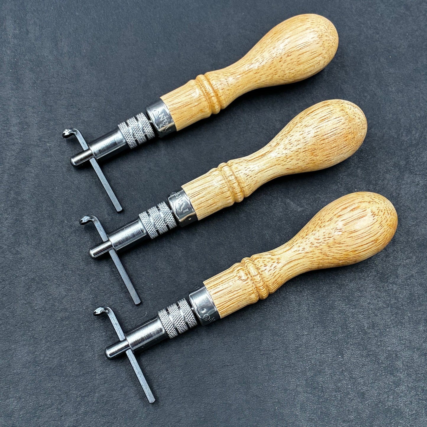 Set aus drei Lederwerkzeugen mit Holzgriff und Metallaufsätzen für Handwerk und Basteln.