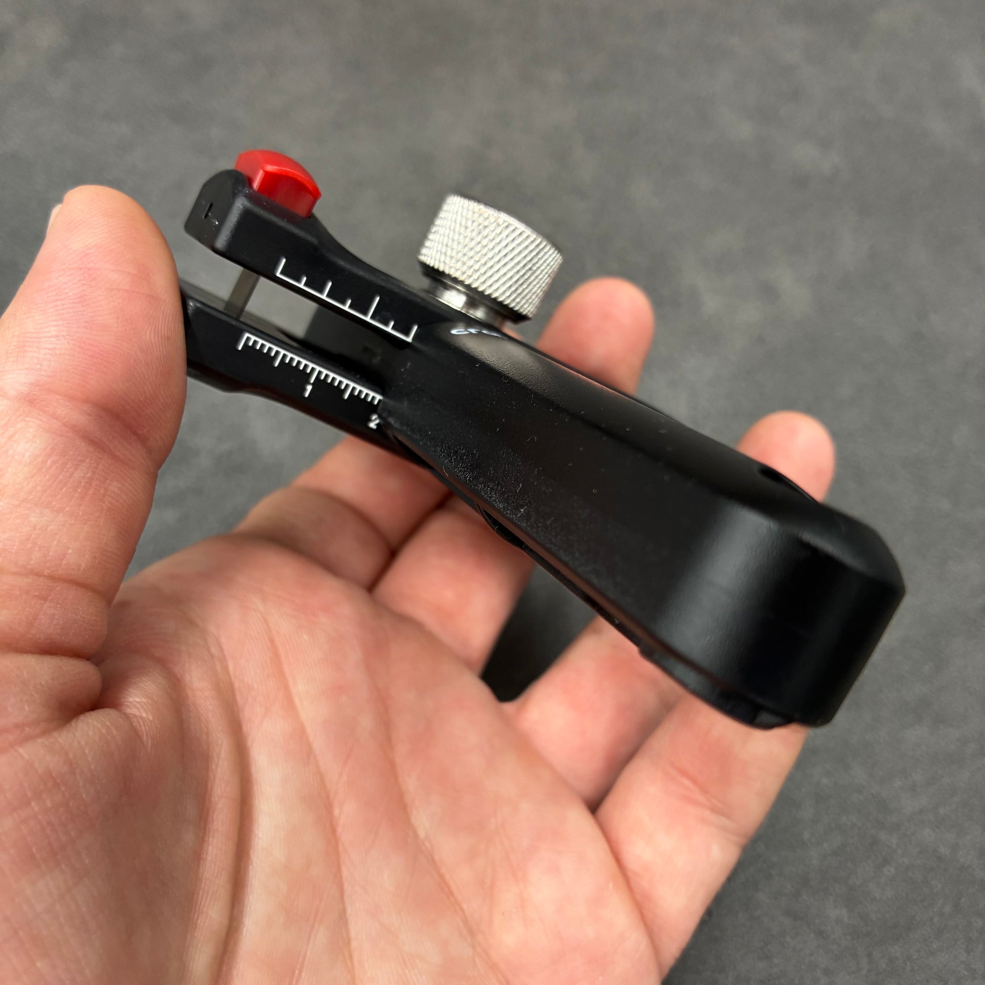 Schwarzes Leder-Messwerkzeug mit Skala und Einstellrad in der Hand.