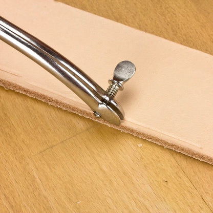 Silbernes Ledereinkerbungswerkzeug auf hellem Naturleder auf Holzuntergrund für Lederbearbeitung