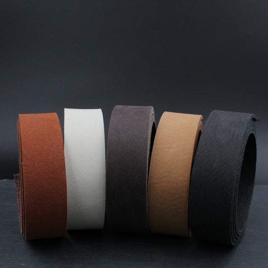 Fünf Lederstreifen in verschiedenen Farben gerollt vor schwarzem Hintergrund für Lederprojekte