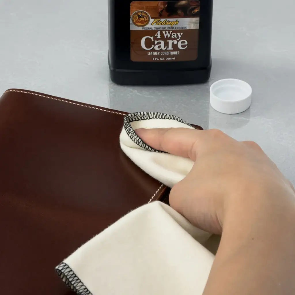 Lederpflege mit weichem Tuch und Lederpflegemittel auf braunem Glattleder