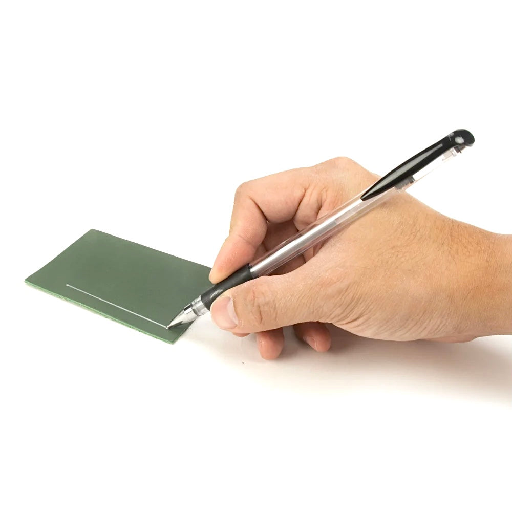 Hand zeichnet mit einem IVAN LEATHERCRAFT Silberstift eine Linie auf grünes Leder.