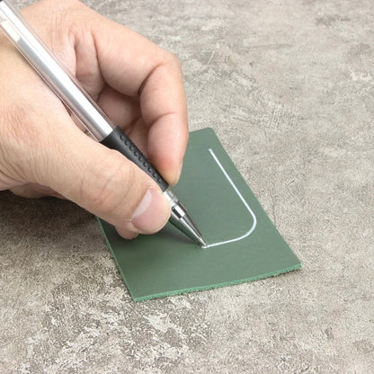 Hand benutzt einen Ivan Leathercraft Silberstift zum Markieren auf grünem Leder.