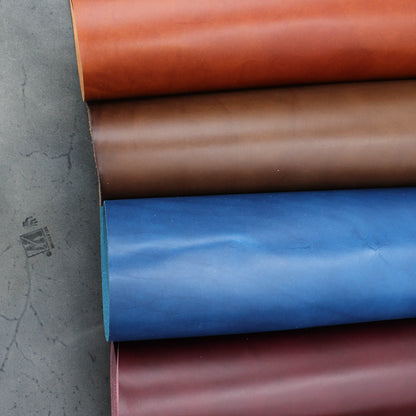 Vier Rollen Walpier Buttero Premium-Leder in den Farben Cognac, Braun, Blau und Weinrot auf grauem Untergrund. Italienisches pflanzlich gegerbtes Vollnarbenleder mit glatter Oberfläche und sichtbarem Walpier-Stempel.