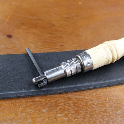 Lederstanzwerkzeug mit Holzgriff zum Stanzen von Löchern in schwarzem Leder.
