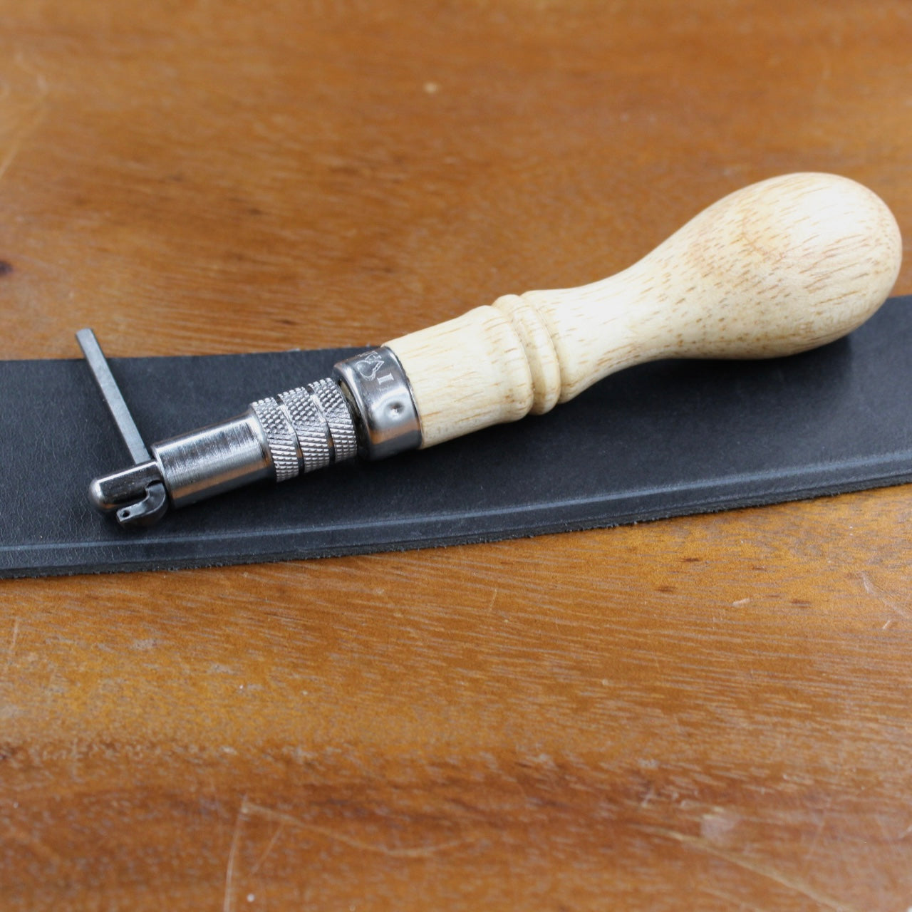 Lochzange und schwarzes Leder auf einem Holztisch für Lederarbeiten