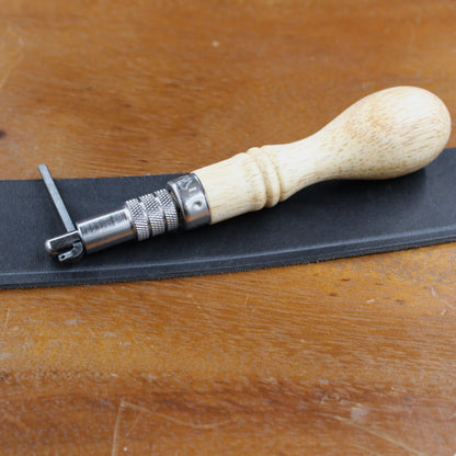 Lochzange und schwarzes Leder auf einem Holztisch für Lederarbeiten