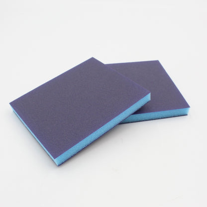 Zwei rechteckige Schleifschwämme von Klever Leder mit blauer Schaumstoffseite und dunkler Schleiffläche.